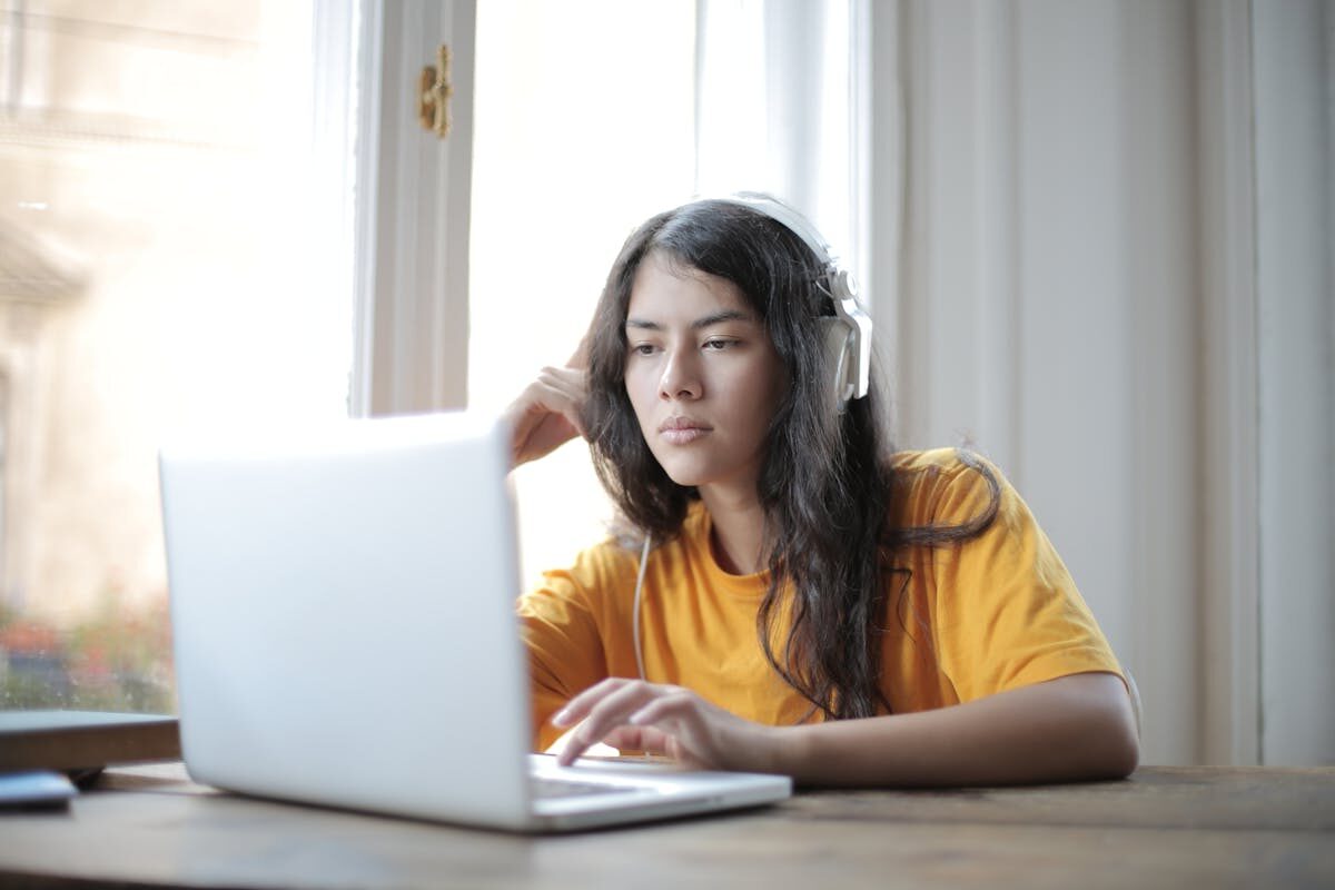 Young woman in headphones focused on laptop work, conveying a digital nomad lifestyle.