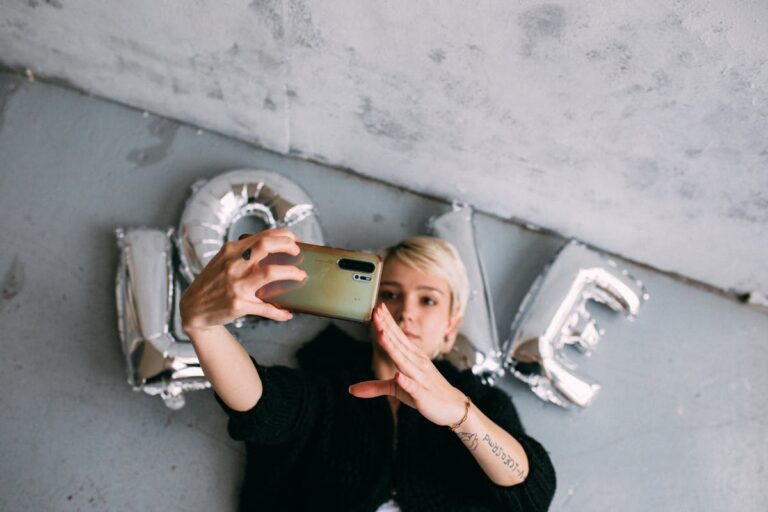 Young woman taking a selfie with love-shaped balloons, showcasing modern lifestyle.