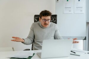 a man in a gray sweater using a laptop