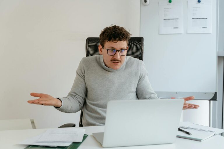 a man in a gray sweater using a laptop
