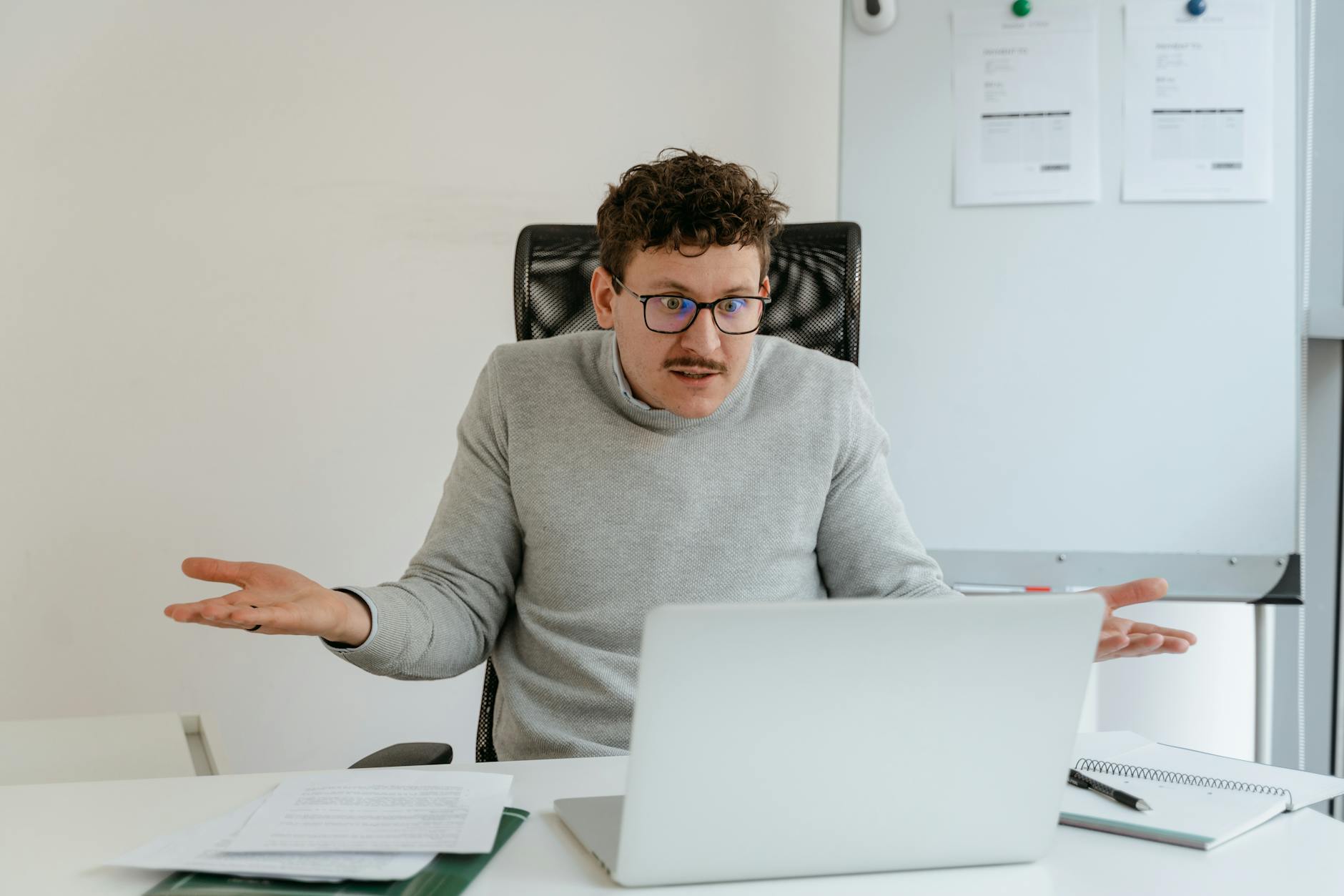 a man in a gray sweater using a laptop